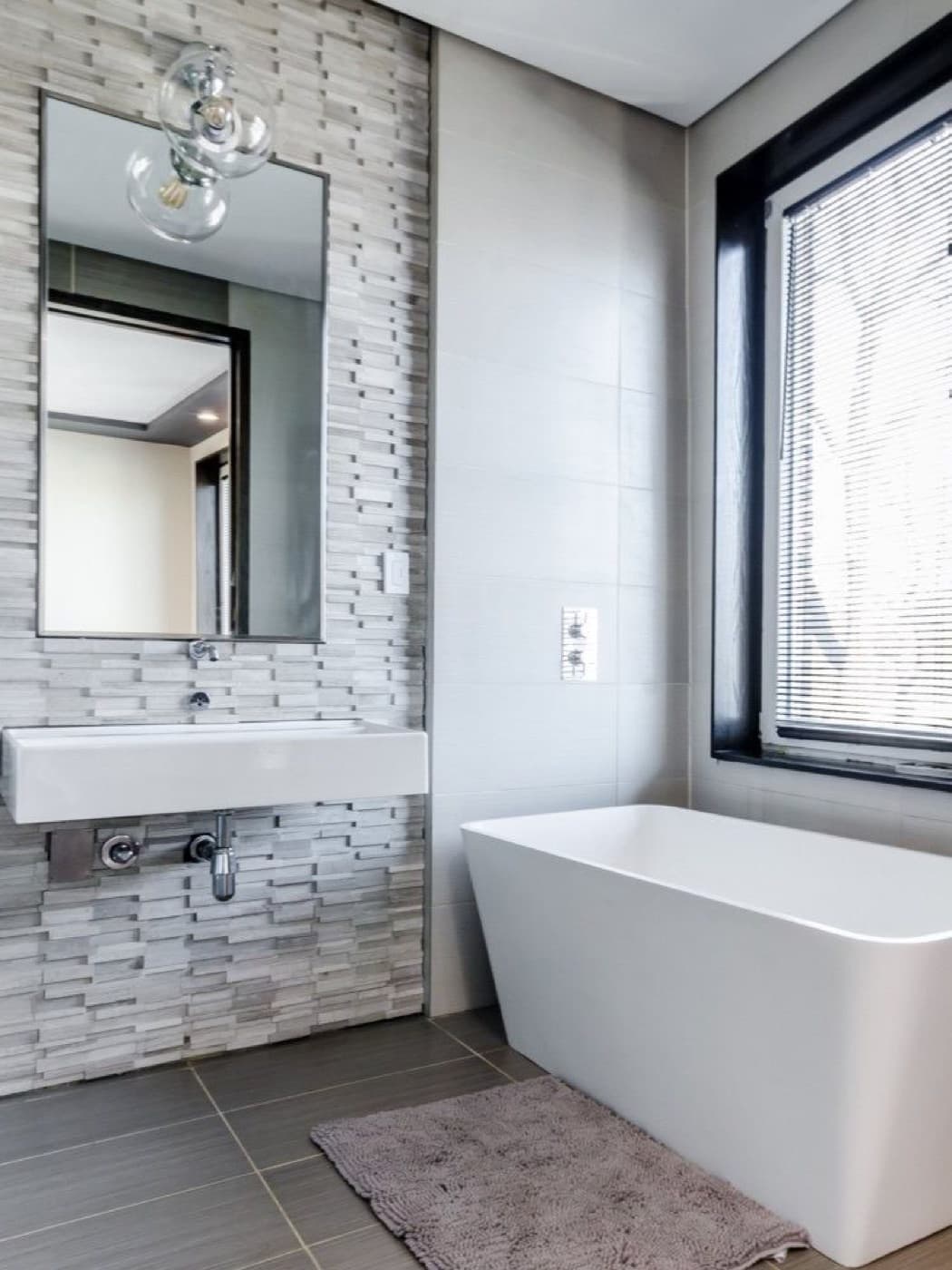 Moderne badkamer met vrijstaand bad, mozaïekwand en zwarte kozijnen