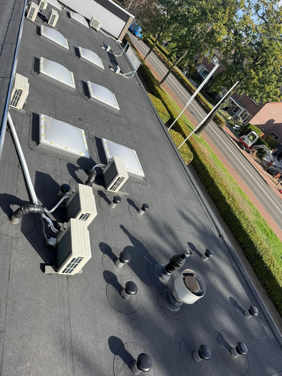 Plat dak van bovenaf gezien met lichtkoepels, ventilatie en airco-units